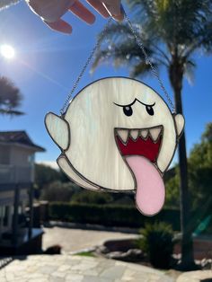 a hand holding up a cartoon character hanging from a chain