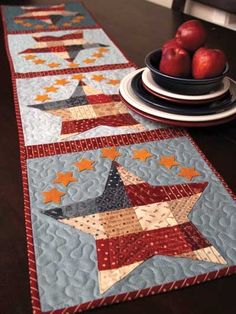 the table runner is decorated with red, white and blue quilted stars on it