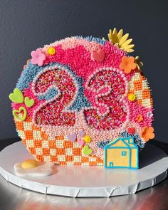 the cake is decorated like an owl and has flowers on it's head, with a house in the background