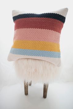 a multicolored pillow sitting on top of a stool