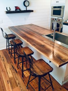 a kitchen counter with four stools in front of it and a clock on the wall