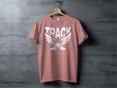 Show off your love for track and field with this stylish and comfortable Running Tee TNF XC. This Run Track and Field Shirt is perfect for runners of all levels. Running Tee TNF XC This modern track and field t-shirt features a bold design of winged running shoes with "TRACK" emblazoned above. Made with premium Airlume cotton, this super-soft unisex tee is available in a variety of heather colors. The classic fit is flattering on everyone, and the side seams provide a contoured look. Run Track a Casual Pink Activewear With Graphic Print, Casual Red Graphic Print Activewear, Sporty Running T-shirt With Logo Print, Casual Running T-shirt With Logo Print, Sporty Letter Print T-shirt For Running, Casual Running T-shirt, Sporty Activewear With Graphic Print And Comfortable Fit, Sporty Printed Activewear For Streetwear, Casual Athletic Fit T-shirt For Running