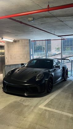 a black sports car parked in an empty parking garage next to a red fire hydrant