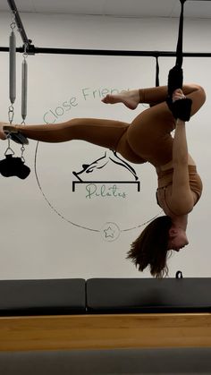 a woman doing aerial acrobatics on a balance beam in an exercise room