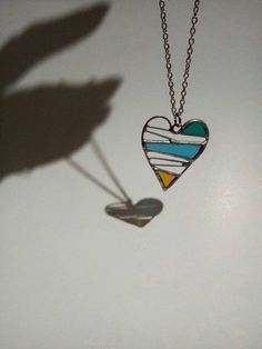 the shadow of a person's hand and a heart shaped necklace