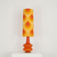 an orange and yellow lamp sitting on top of a white table