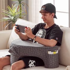 a young man sitting on a couch holding a tablet