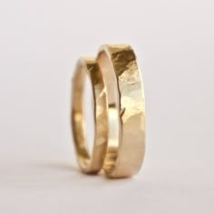 two gold wedding bands are shown against a white background, one is slightly bent to the side