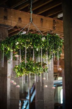 a chandelier hanging from the ceiling with greenery and beads attached to it