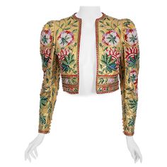 An extremely gorgeous one-of-a-kind Lanvin haute couture metallic gold lamé cropped jacket dating back to the late 1970's. The fabric itself is a masterpiece; sparkling gold snakeskin patterned lamé lavishly embroidered with colorful chain-stitch flowers and vinery. This work must have taken weeks to complete. Exquisite beadwork in matching hues adds beautiful depth and texture. I love the chic puff-shoulders and lean, long sleeves. The open front body-skimming shape really adds to the jacket's Stitch Jacket, Haute Couture Gowns, Paris Couture, Jeanne Lanvin, Vintage Chain, Gold Lame, Fashion District, Linen Jackets, Coat Design