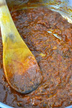 a wooden spoon in a pot filled with chili