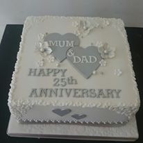 a white cake with silver hearts and the words mum & dad on it is sitting on a table