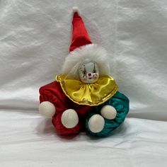 a stuffed toy clown sitting on top of a white sheet