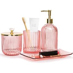 pink glass bathroom accessories including toothbrush and soap dispenser