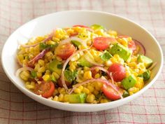 a white bowl filled with corn and veggies on top of a checkered table cloth