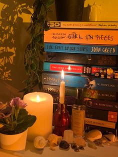 a candle and some books are sitting on a table next to a potted plant