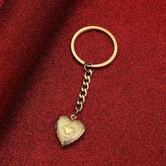 a gold heart shaped keychain on a red cloth with a chain attached to it