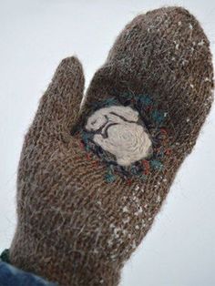 a person's hand wearing a brown mitt with a white dog embroidered on it