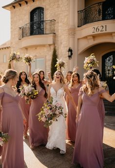 a group of women standing next to each other in front of a building with flowers on their heads