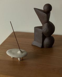 a small white object sitting on top of a wooden table next to a black sculpture