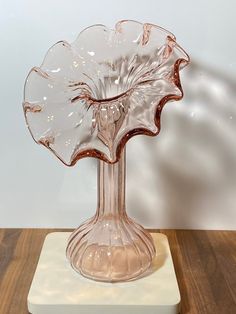 a clear glass vase sitting on top of a wooden table next to a white wall