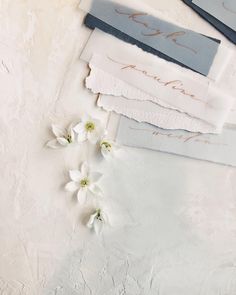 some white flowers are sitting next to papers and pens on a table with writing in them