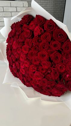 a large bouquet of red roses in a white paper wrapper