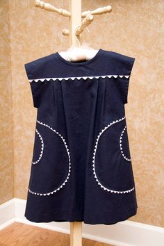 a dress hanging on a clothes rack in front of a wall with a wooden hanger