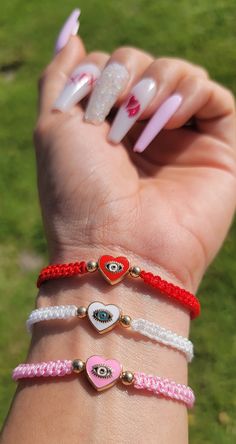 a woman's hand with four different bracelets on her wrist and two hearts