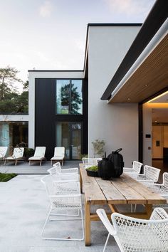 a wooden table sitting on top of a patio next to a white chair and potted plant