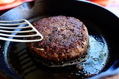 a hamburger being cooked in a skillet with a fork