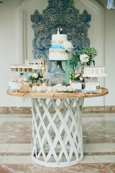 a table topped with cakes and cupcakes on top of a tiled floor next to a wall