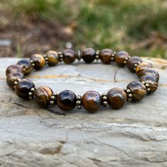 Handmade Genuine Stone Bracelets High-Quality Beaded Bracelet Genuine 8mm Tiger Eye Stone Beads Stretch Bracelet Made With Quality Cord & Antique Bronze Spacers Made With Pure Positive Energy Tiger Eye Properties - Will & Courage - Luck & Success - Prosperity - Grounding & Physical Vitality These Quality Bracelets Will Add A Touch Of Casual Elegance To Your Wardrobe For Any Season Of The Year. All Bracelets Come Carefully Packaged In A Gift Box Ready For Giving. Brown Spiritual Bracelet With Spacer Beads, Spiritual Brown Bracelet With Spacer Beads, Adjustable Brown Bracelets With Faceted Beads, Adjustable Brown Bracelet With Faceted Beads, Brown Bracelets With 8mm Beads, Brown 8mm Beaded Round Bracelets, Brown Gemstone Beaded Bracelets, Brown Round Bracelets With 8mm Beads, Brown Bracelet With 8mm Round Beads