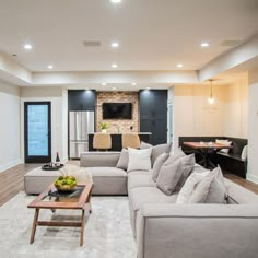 a living room filled with furniture and a flat screen tv mounted to the wall next to a kitchen