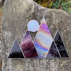 three triangle shaped glass pieces sitting on top of a large rock in front of some grass