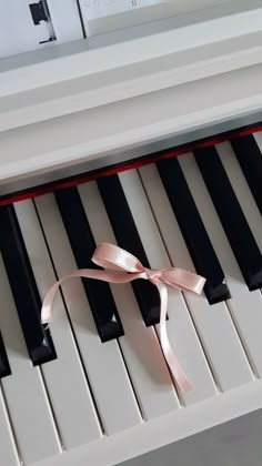 a pink ribbon is on the keys of a piano