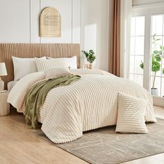 a bed with white and green comforters in a bedroom