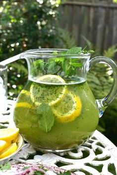 a pitcher filled with green liquid and lemon slices