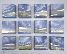 nine square paintings with blue and yellow clouds in them on a white wall above the ocean