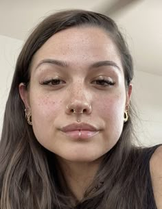 a woman with freckles on her nose and nose piercings is looking at the camera