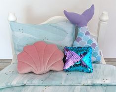 a bed with mermaid themed pillows on top of it and a pink pillow in the shape of a starfish