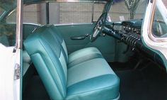 the interior of an old car with blue leather seats