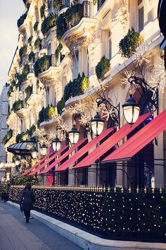 a person walking down the street in front of a building with christmas lights on it