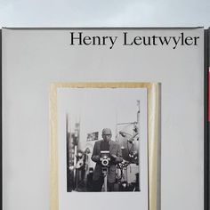 an old black and white photo of a man holding a camera in front of a sign