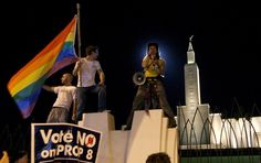 some people standing on top of a building with a rainbow flag in front of them