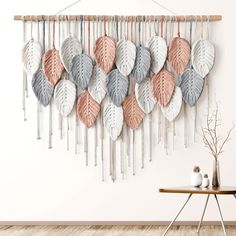 a wall hanging with many different colored leaves on it and a table in front of it