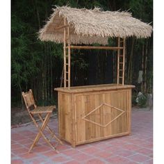 an outdoor bar with a straw roof and bamboo barstools in front of it