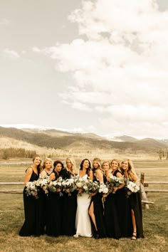 a group of women standing next to each other in front of a fence with flowers