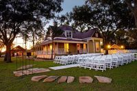 an outdoor wedding venue with rows of white chairs set up in front of the house