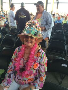 a woman wearing a colorful hat sitting in a stadium